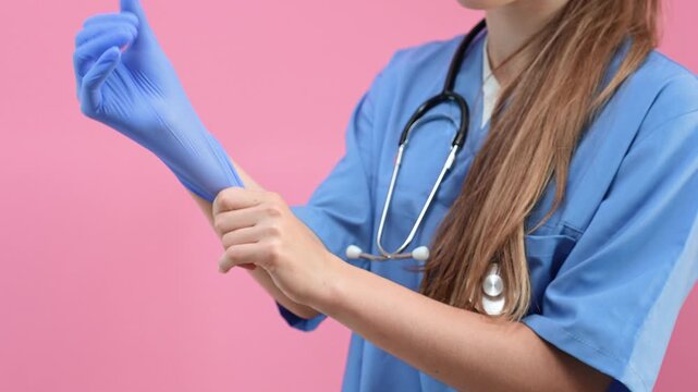 A doctor in a blue uniform puts on gloves against an isolated background