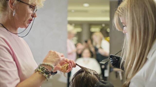Hairdresser treating client's hair in beauty salon. Process of applying device to hair.
