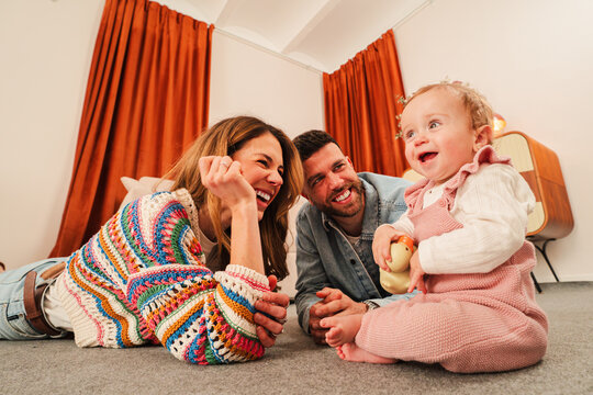A delightful family moment captured as parents enjoy playful interactions with their baby, creating joyful memories filled with laughter and love in a cozy and warm atmosphere of togetherness.