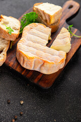 Washed rind cheese soft cheese with orange rind munster french cheese tasty snack fresh delicious gourmet food background on the table rustic top view copy space