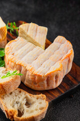 Washed rind cheese soft cheese with orange rind munster french cheese tasty snack fresh delicious gourmet food background on the table rustic top view copy space