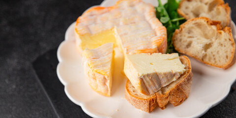 Washed rind cheese soft cheese with orange rind munster french cheese tasty snack fresh delicious gourmet food background on the table rustic top view copy space