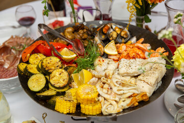 A large metal pan filled with a variety of grilled and roasted foods