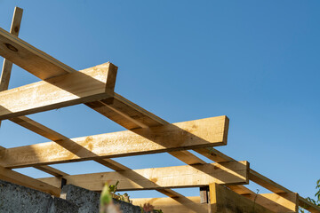Wooden construction frame with beams against blue sky. Architectural detail and building structure concept.