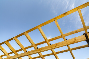 Wooden construction frame with beams against blue sky. Architectural detail and building structure concept.