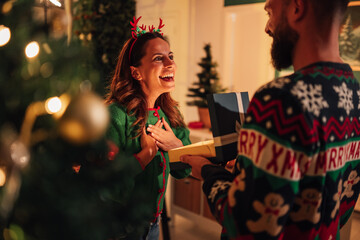 Happy couple exchanging christmas gifts at home