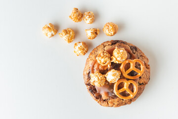 Fresh chocolate American chip cookie decorated with salted camel and caramel popcorn on white background. Flat lay of cookies with peanut butter filling inside