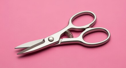 Metal scissors lying on a pink surface close up