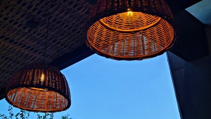 Lampshades are woven from wicker and hung on the summer veranda with lights on