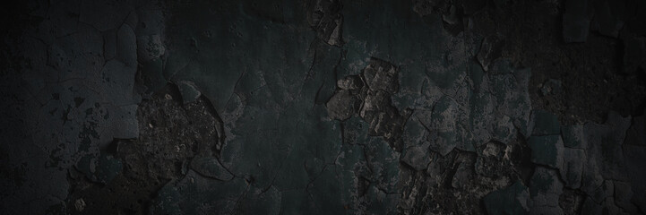 Dark wide panoramic background. Peeling paint on a concrete wall. Dark grunge texture of old cracked flaking paint. Weathered rough painted surface. Patterns of cracks. Darkness background for design.