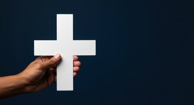 Man hand holding a white cross on dark background, representing Christian faith, religion, and spirituality concept with copy space. - Powered by Adobe