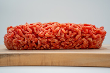 Side front view of frozen minced beef mixed with vegetables, presented in a flat layer and isolated on a clean white background. Ideal for food packaging, cooking ingredients, meal preparation, and gr