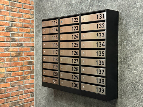 Shiny modern mailboxes for letters and correspondence with numbers. Modern metallic mailboxes with numbers in the lobby of a residential or office building close-up. Mailboxes for emails.  - Powered by Adobe