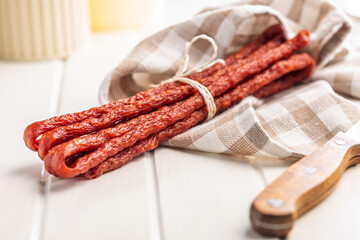 Smoked kabanos. Mini dried thin sausages on cutting board.