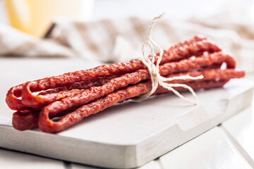 Smoked kabanos. Mini dried thin sausages on cutting board.