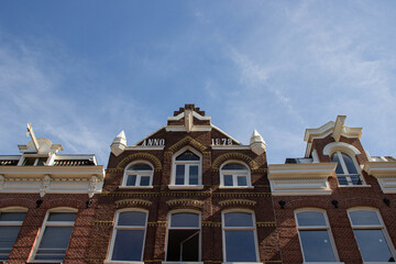 Historic brick building with ornate architectural details, showcasing large windows and decorative elements against a clear blue sky, representing classic urban design and heritage
