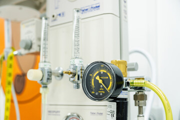 Close-up of a vacuum gauge displaying negative pressure readings, attached to complex medical equipment within a hospital setting, ensuring accurate monitoring and control for patient care