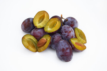 Whole and halved plums, white background. Fresh organic fruit