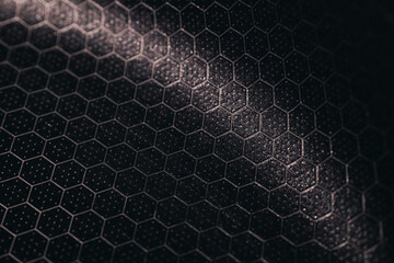 Close-up of a textured hexagonal pattern on a dark metallic surface with subtle dotted detailing, creating a modern industrial and geometric background.