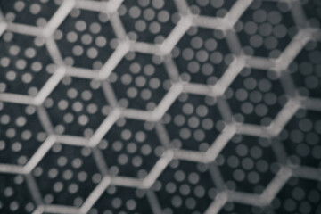 Defocused close-up of a hexagonal pattern with dotted texture on a dark surface, creating an...