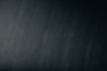 Obraz premium Blurred close-up of a brushed dark metal surface with diagonal line texture, creating an abstract industrial background with subtle gradients and shading.