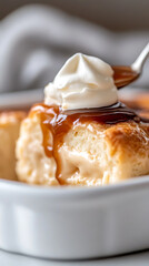Close-up of flan dessert topped with whipped cream and caramel sauce. Served in a square bowl. Silver spoon placing cream on the flan.