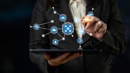 A business professional engages with digital icons on a tablet, symbolizing modern technology and...