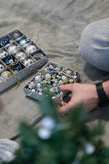 Male hand holding box with Christmas decorations.