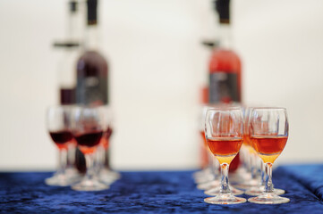 Glasses of red and orange wine with bottles on blue cloth