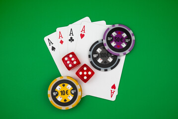 Four aces poker hand with colorful casino chips and dice on green table &ndash; symbol of gambling, luck, risk, addiction and casino games.