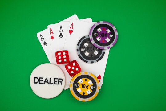 Four aces poker hand with colorful casino chips, dice and dealer button on green table &ndash; symbol of gambling, luck, risk, addiction and casino games.
