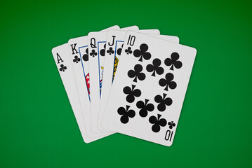 Royal flush in clubs on green table, symbolizing ultimate poker hand, casino gambling, and high-stakes games.