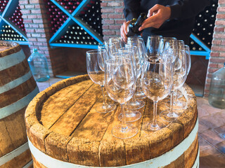Many glasses of white wine on wooden barrel. Wine tasting event. Wine cellar with wine barrels. French wooden barrels. Wine shop wine bar winery or wine tasting concept