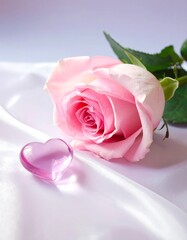 A delicate pink rose rests on a soft, smooth surface, accompanied by a translucent heart-shaped crystal, evoking a sense of romance and beauty.