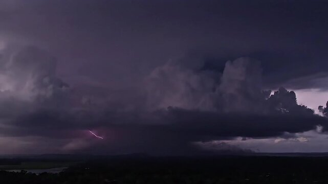Dramatic storm clouds with lightning flash over a landscape.