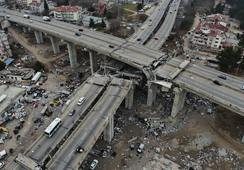 Devastating earthquake damage to an elevated highway overpass with vehicles visible