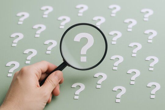 Magnifying Glass Over Question Marks Concept: Exploring Answers, Curiosity and Information Seeking on Green Background