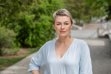 Portrait of a beautiful middle-aged woman in a summer park