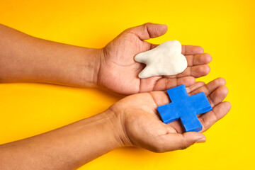 Two open hands holding a tooth and a medical cross illustrating dental treatment options patient choice and compassionate healthcare service.

