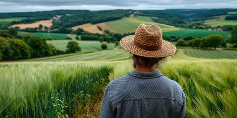 A man in a hat gazes at a vast, golden wheat field under a cloudy sky, embodying reflection and tranquility. The image captures serenity, nature&rsquo;s beauty, and peaceful solitude.