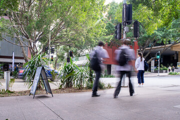 People walking on city footpath with motion blur in urban street environment