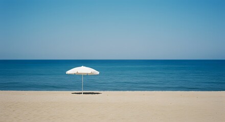 A solitary umbrella on a sandy beach against the tranquil sea and sky, representing the bliss of summer