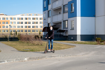 Young man riding electric scooter in city park