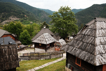 Wooden roofs and cottages in the Ethno village of Drvengrad, surrounded by lush green hills in spring