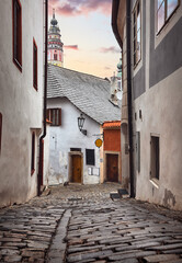 Cesky Krumlov (Czech Krumlov), Czech Republic. View at Castle Tower from the narrow street with medieval architecture in the ancient bohemian village with antique houses. Evening time romantic place.