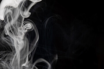 Elegant swirls of white smoke rise against a dark background
