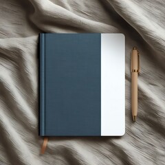 A blue notebook with a white section and a gold pen on a textured fabric surface