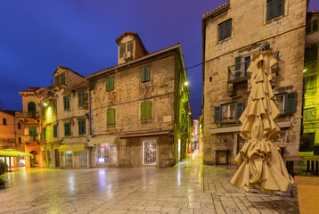 Traditional stone buildings with wooden shutters in the old town of Split Croatia illuminated in the evening.