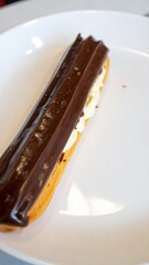 French Chocolate &Eacute;clair Pastry with Cream Filling Served on White Plate for Premium Dessert Object and Gourmet Food Concept