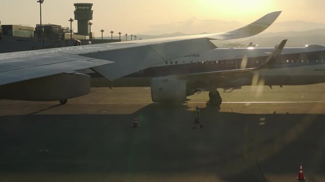 An airliner slowly pulls into a parking spot on the tarmac during a golden hour sunset in Sendai, 2025.09.16.